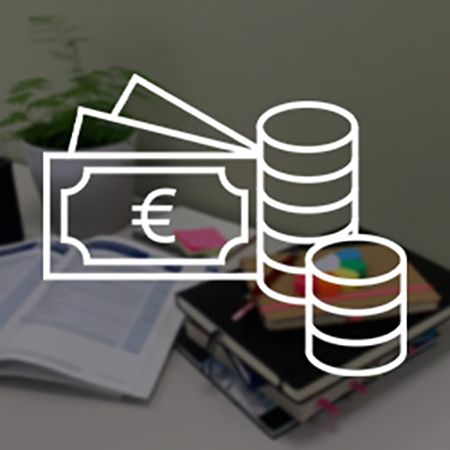Ein aufgeräumter Schreibtisch mit Büchern, einem offenen Notizbuch, bunten Haftnotizen und einem kleinen Pflanzentopf. Überlagert wird das Bild von einem weißen Piktogramm, das Geldscheine mit einem Euro-Symbol und gestapelte Münzen darstellt.