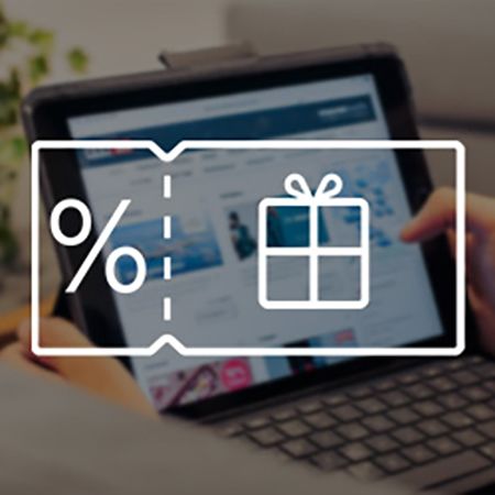 Eine Person hält ein Tablet in der Hand, auf dem eine Webseite mit verschiedenen Angeboten angezeigt wird. Im Hintergrund sind Pflanzen und ein unscharfer Schreibtisch zu erkennen. Überlagert wird das Bild von einem weißen Piktogramm, das einen Gutschein mit einem Prozentzeichen und ein Geschenk symbolisiert.